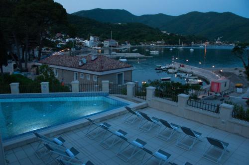 a swimming pool with chairs next to a body of water at Boutique Hotel Kredo in Herceg-Novi