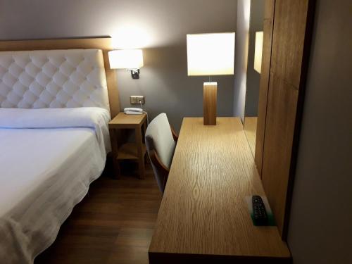 a hotel room with a bed and a desk with a telephone at Hospedería Santa Elena in San Carlos del Valle