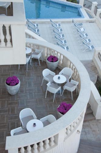 a balcony with tables and chairs next to a pool at Boutique Hotel Kredo in Herceg-Novi