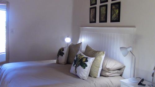 a bedroom with a white bed with pillows at Forest Nest Cottage, Tsitsikamma in Stormsrivier