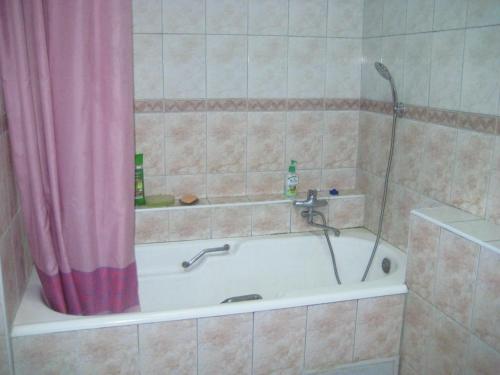 uma casa de banho com uma banheira e uma cortina de chuveiro rosa. em ShymHostle em Shymkent