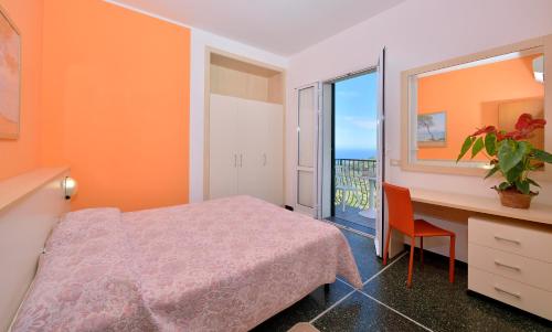 a bedroom with a bed and a desk and a window at Residence Elvira in Diano Marina