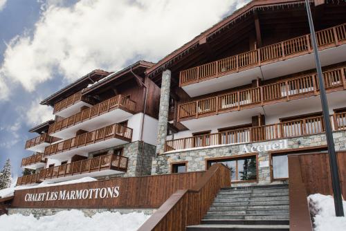 Un edificio con balcones y escaleras de madera en la nieve. en CGH Résidences & Spas Chalet Les Marmottons, en La Rosière