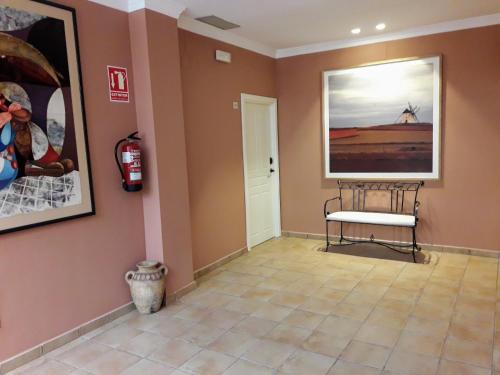 a room with a bench and paintings on the walls at Hospedería Santa Elena in San Carlos del Valle