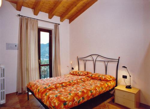 a bedroom with a bed with an orange bedspread and a window at Residence Garden in Tignale