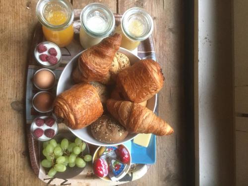 einen Teller mit Croissants, Obst und Getränken in der Unterkunft De Groene Maan in Mechelen