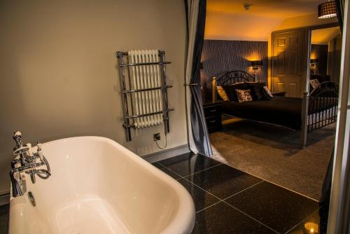 a bathroom with a white tub and a living room at Mount Stewart Hotel in Portpatrick
