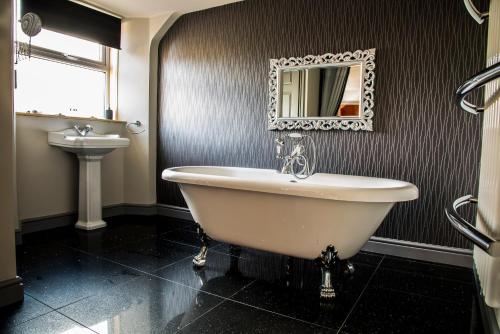 a bathroom with a tub and a sink and a mirror at Mount Stewart Hotel in Portpatrick