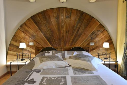 a large bed with a wooden headboard and two lamps at Vecchio Mulino Guest House in Aosta