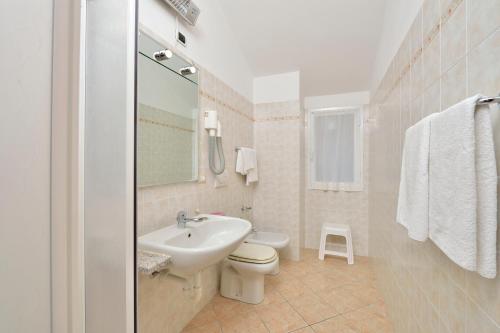 a white bathroom with a sink and a toilet at Residence Elvira in Diano Marina