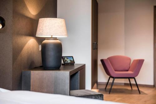 a bedroom with a lamp and a pink chair at Hotel - Appartements Schmied Hans in Schenna