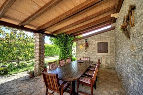 um pátio com uma mesa de madeira e cadeiras em Villa Orbanici em Barban