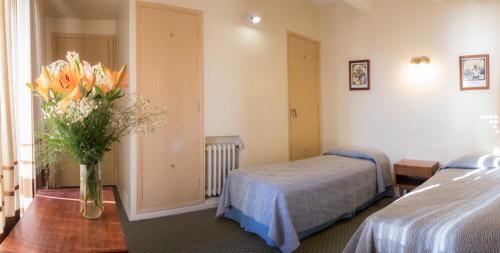 a hotel room with two beds and a vase of flowers at Hotel King's in Mar del Plata
