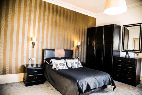 a bedroom with a bed and a dresser and a mirror at Mount Stewart Hotel in Portpatrick