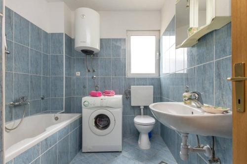 ein Badezimmer mit einer Waschmaschine und einem Waschbecken in der Unterkunft Apartments Ukic - with large outdoor pool in Kaštela