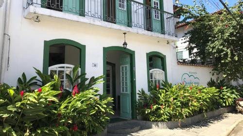 a building with green doors and a balcony at Pousada Sonho Meu in Paraty