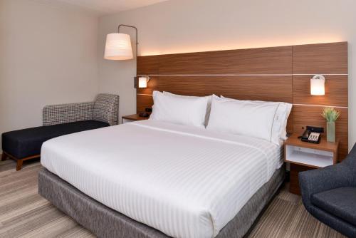 a hotel room with a large bed and a chair at Holiday Inn Express & Suites - St. Petersburg - Madeira Beach by IHG in St. Petersburg
