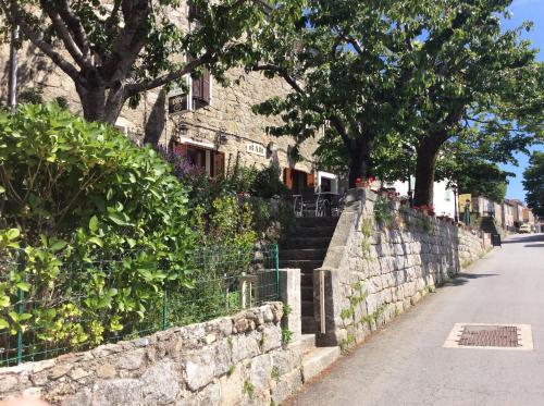 a stone wall with stairs and trees on a street at Hotel Restaurant de la Poste in Aullène