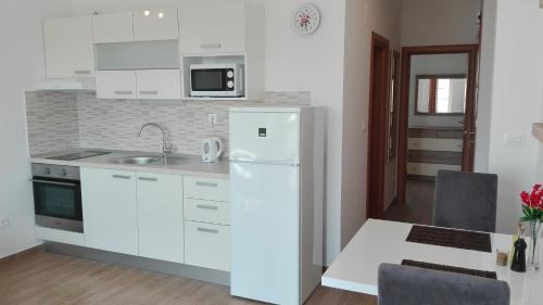 a kitchen with white cabinets and a white refrigerator at Šibenska oaza in Šibenik