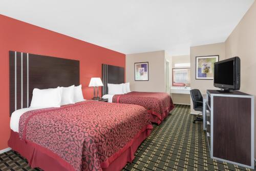 a hotel room with two beds and a flat screen tv at Days Inn by Wyndham College Station University Drive in College Station