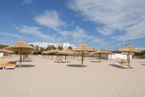 a beach with many straw umbrellas and lounge chairs at Yadis Hammamet in Hammamet