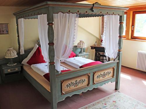 a bedroom with a canopy bed with red pillows at Hotel Adlerschanze in Schönwald