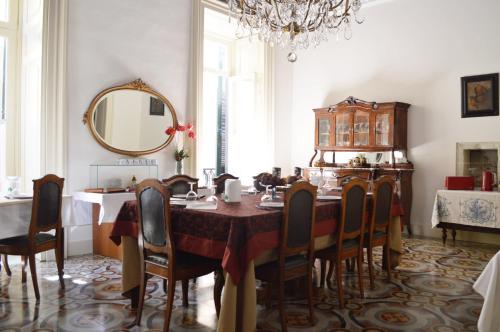 una sala da pranzo con tavolo, sedie e specchio di Palazzo Rollo a Lecce