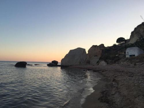 een strand met rotsen en de oceaan bij zonsondergang bij Alloggio S. Agostino in Sciacca