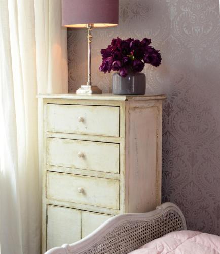 a dresser with a lamp and a vase of flowers on it at Hotel No. 11 in Lüdinghausen