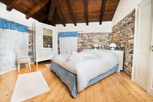 a bedroom with a bed and a stone wall at Villa Pinetina B&B in Lasnigo