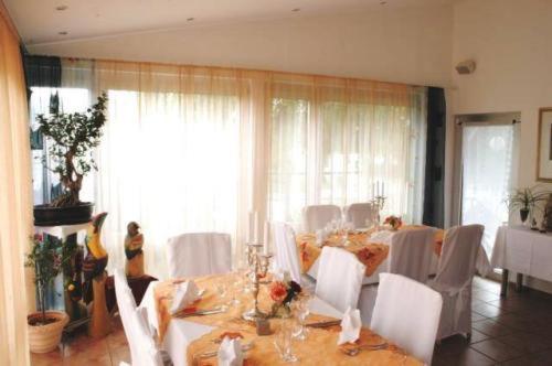 a dining room with white tables and white chairs at Hotel Adler in Aichelberg