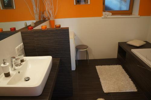 baño con lavabo blanco y pared de color naranja en Appartements Sonngarten en Campo Tures