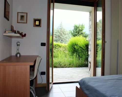a bedroom with a door open to a garden at Casa Lella with pool and garden in Lenno