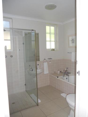 a bathroom with a shower and a toilet and a sink at Manor on the Bay in Gordonʼs Bay