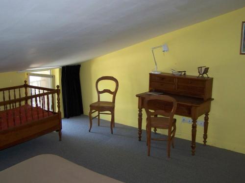 1 Schlafzimmer mit einem Schreibtisch, 2 Stühlen und einem Bett in der Unterkunft Gite le sorgho in Grisolles