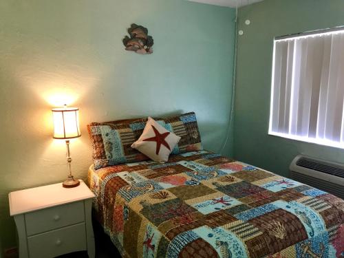a bedroom with a bed and a lamp on a night stand at South Beach Inn - Cocoa Beach in Cocoa Beach