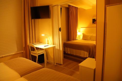 a hotel room with a bedroom with two beds and a desk at Promar - Eco Beach & Spa Hotel in Maceira