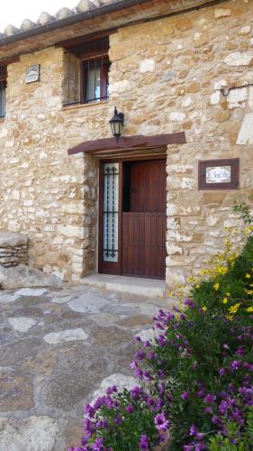a stone building with a wooden door and flowers at Casa Rural Mas de Sant Pau - Turistrat. in Albocácer