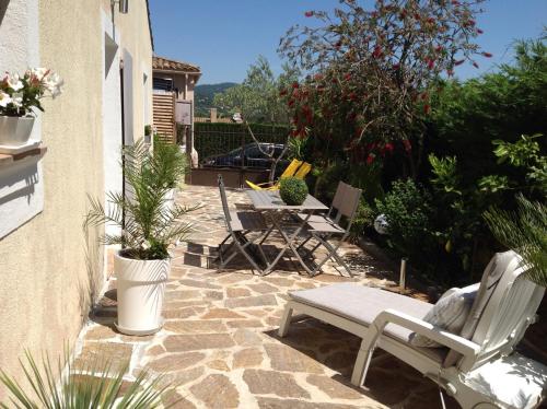 un patio avec des chaises, des tables et des plantes en pot dans l'établissement Maison d'hôtes Antoinette, à Cogolin