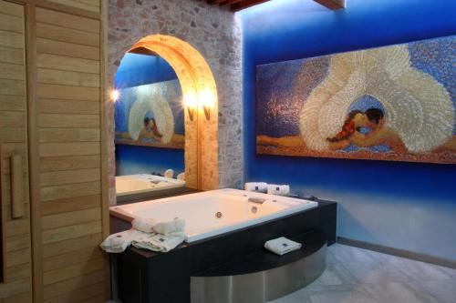 un bagno con una grande vasca e un grande dipinto di Casona de la Republica Hotel Boutique & SPA a Querétaro