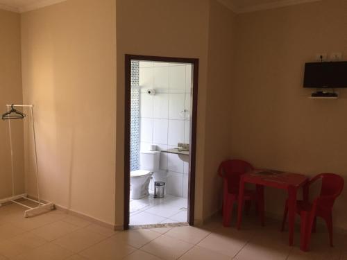 a bathroom with a toilet and a table and chairs at Hotel Pousada Braúna in Braúna