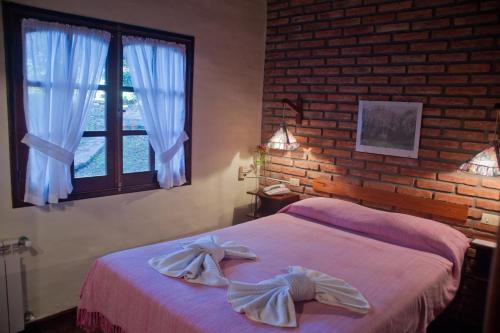 a bedroom with a bed and a brick wall at Cabañas del Golf in La Cumbre