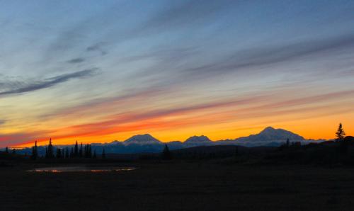a sunset with mountains in the background at Caribou Lodge Alaska in Talkeetna