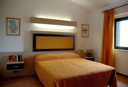 ein Schlafzimmer mit einem Bett mit gelber Tagesdecke in der Unterkunft Villaggio Santandrea Resort in SantʼAndrea Apostolo dello Ionio
