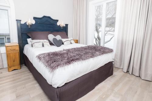 a bedroom with a large bed with a purple blanket at 227 - En bordure de la rivière du Gouffre - Les Immeubles Charlevoix in Baie-Saint-Paul