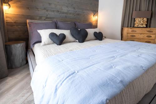 a large bed with two heart pillows on it at 227 - En bordure de la rivière du Gouffre - Les Immeubles Charlevoix in Baie-Saint-Paul