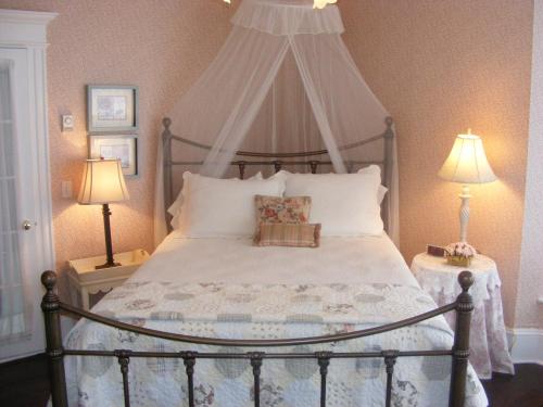 1 dormitorio con 1 cama con dosel y 2 lámparas en Rothesay House Heritage Inn B&B, en Harbour Grace