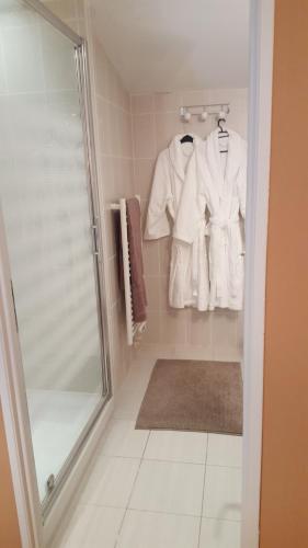 a bathroom with a shower and white robes at Clos des Morillons in Vénérand