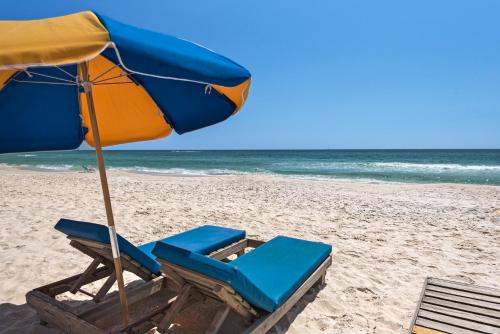 a pair of chairs and an umbrella on the beach at Radisson Beachfront Hotel - Panama City Beach in Panama City Beach