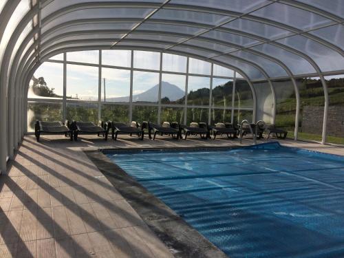 a swimming pool with benches and a large glass building at Vale dos Cocos in Horta
